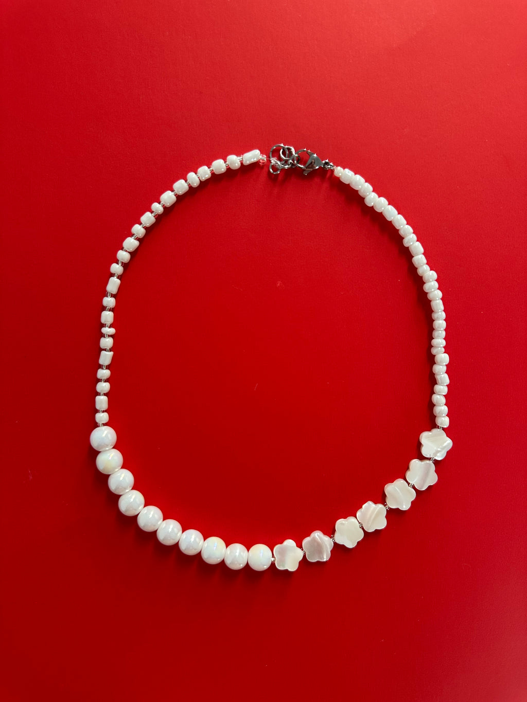 Gros plan du Collier Luna sur fond rouge – détail perles fleurs