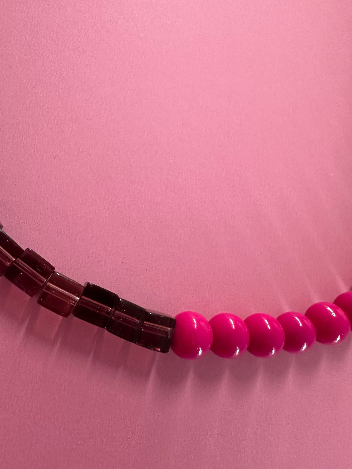 Gros plan du Collier Grenadine – détail perles bordeaux et fuchsia