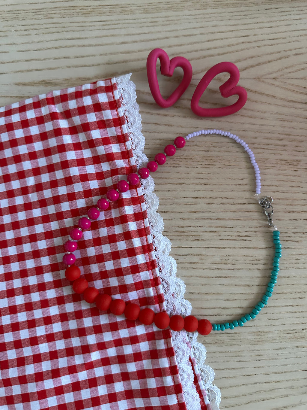Collier Sirène posé sur tissu vichy rouge avec boucles d'oreilles cœur
