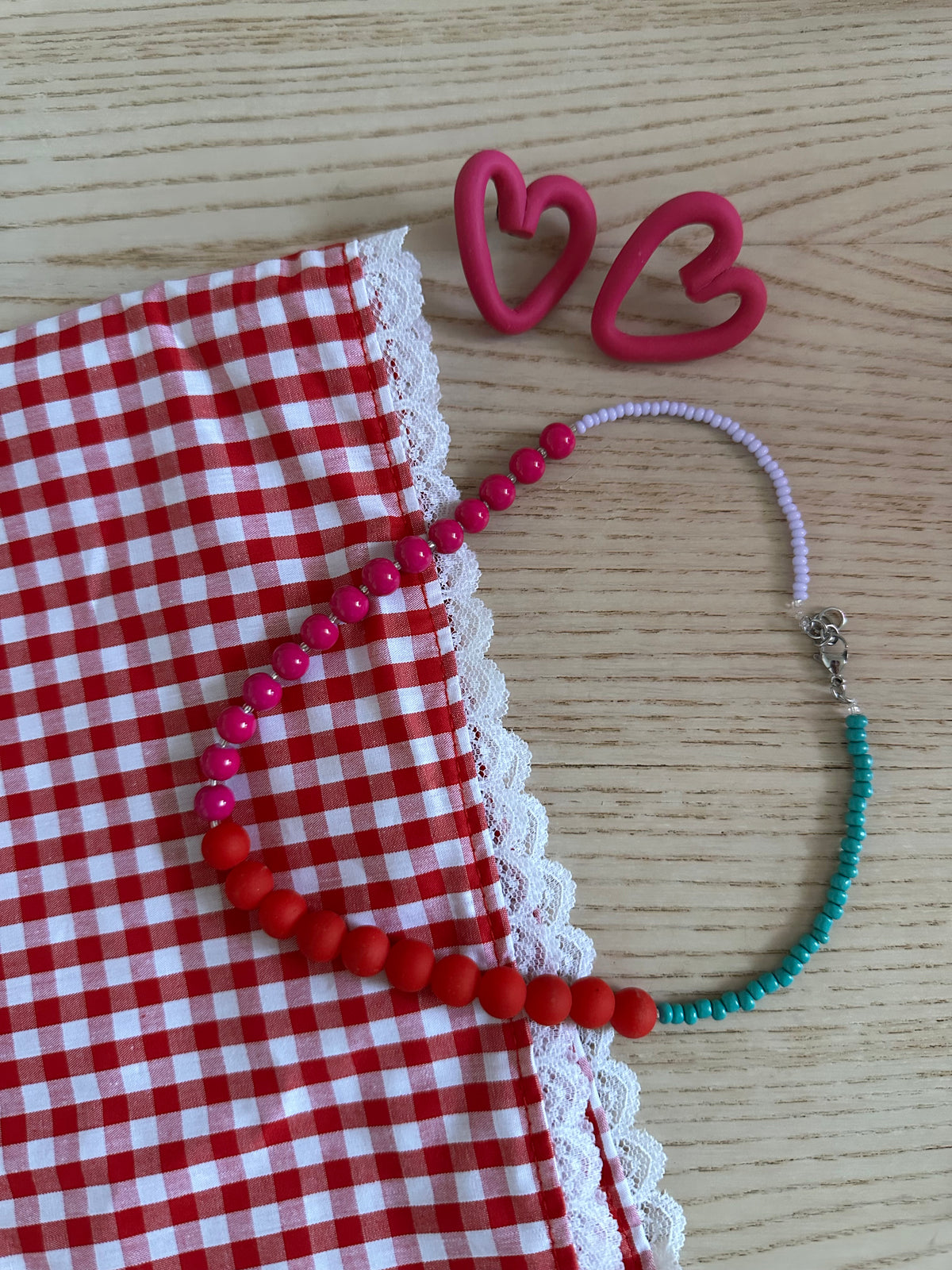 Collier Sirène posé sur tissu vichy rouge avec boucles d'oreilles cœur