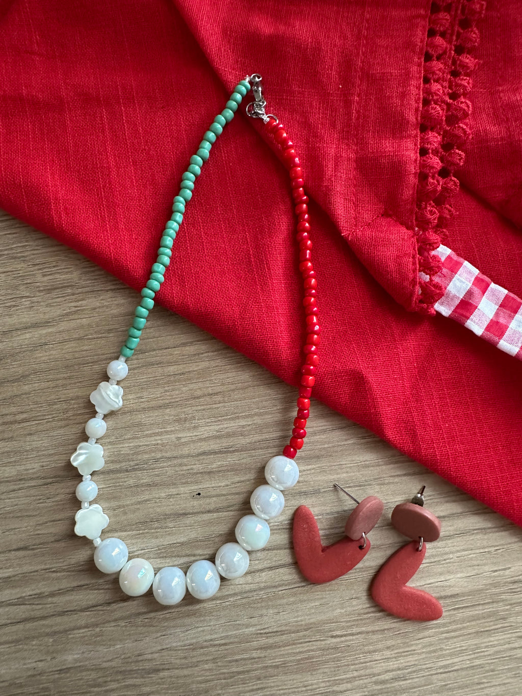 Collier Tropicana posé sur tissu rouge avec boucles d'oreilles cœur terracotta