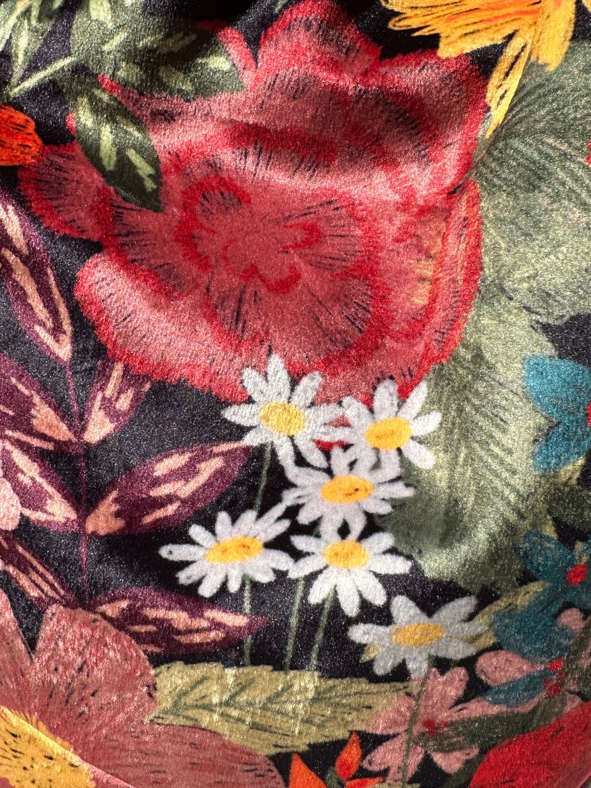 Sac Lisette velours fleuri posé sur une nappe blanche avec un carnet rose