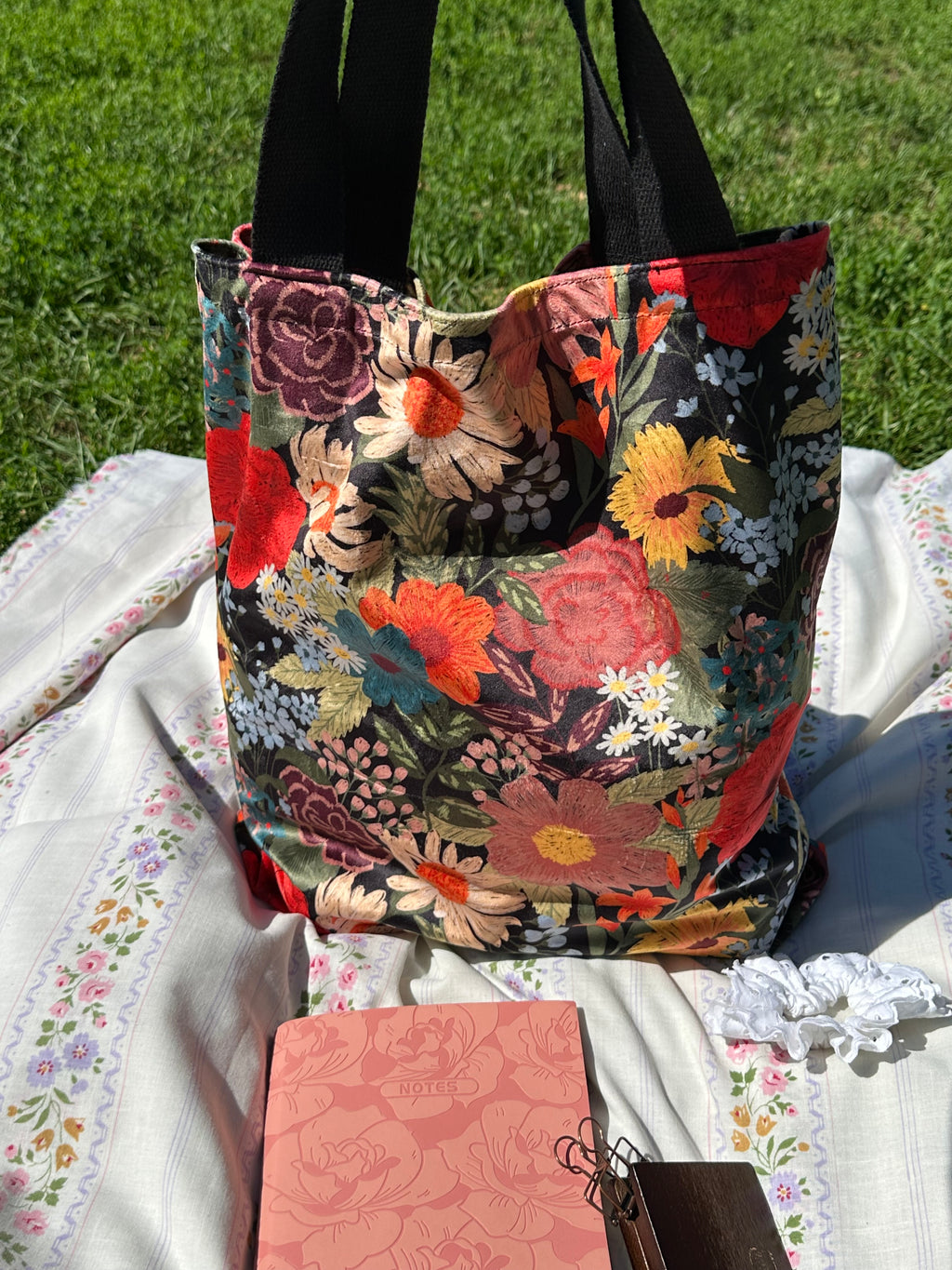 Sac Lisette velours fleuri vu de face sur une nappe fleurie en plein air