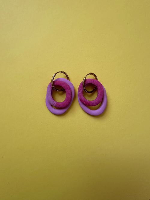 Boucles d'oreilles Nolli - anneaux violet et fuchsia entrelacés sur fond jaune